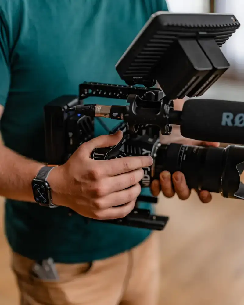 Troy holding a cinema camera rig with a shotgun mic and monitor