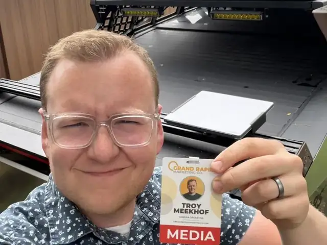 Troy holding up a media badge in front of his Cybertruck's open bed