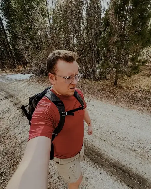 Troy taking a selfie on a forest trail with a backpack on