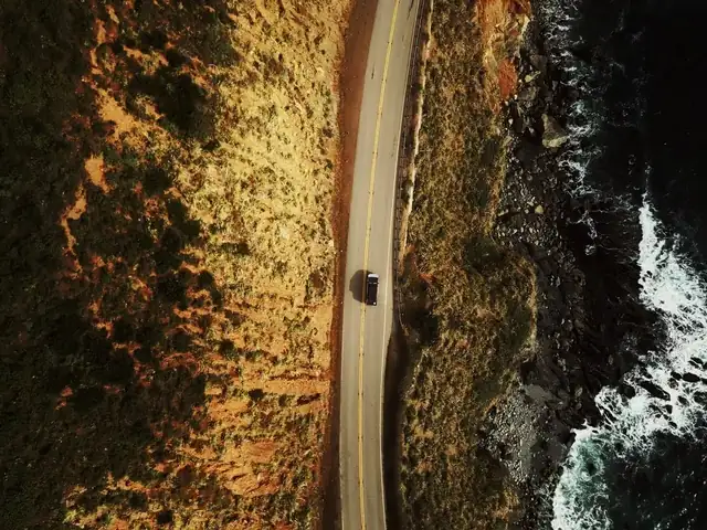 Overhead drone view of a road along the rocky Big Sur shoreline