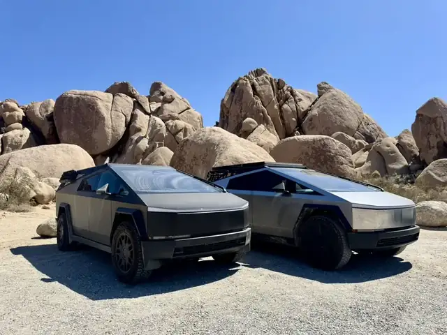 Two Cybertrucks parked in front of granite boulders in Joshua Tree