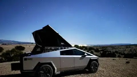 Cybertruck with a rooftop tent pitched at a campsite under a night sky